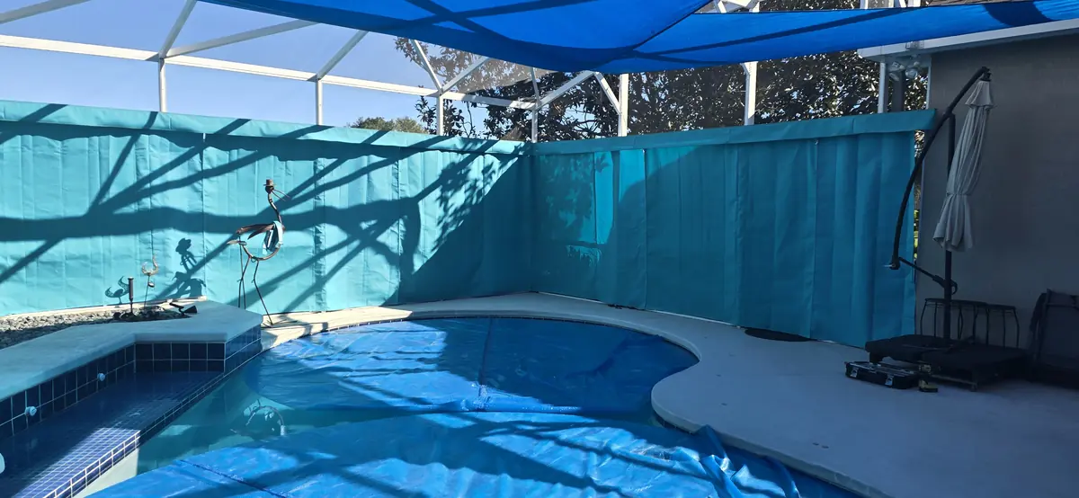 Aqua privacy curtains and a blue shade sail around a pool and spa