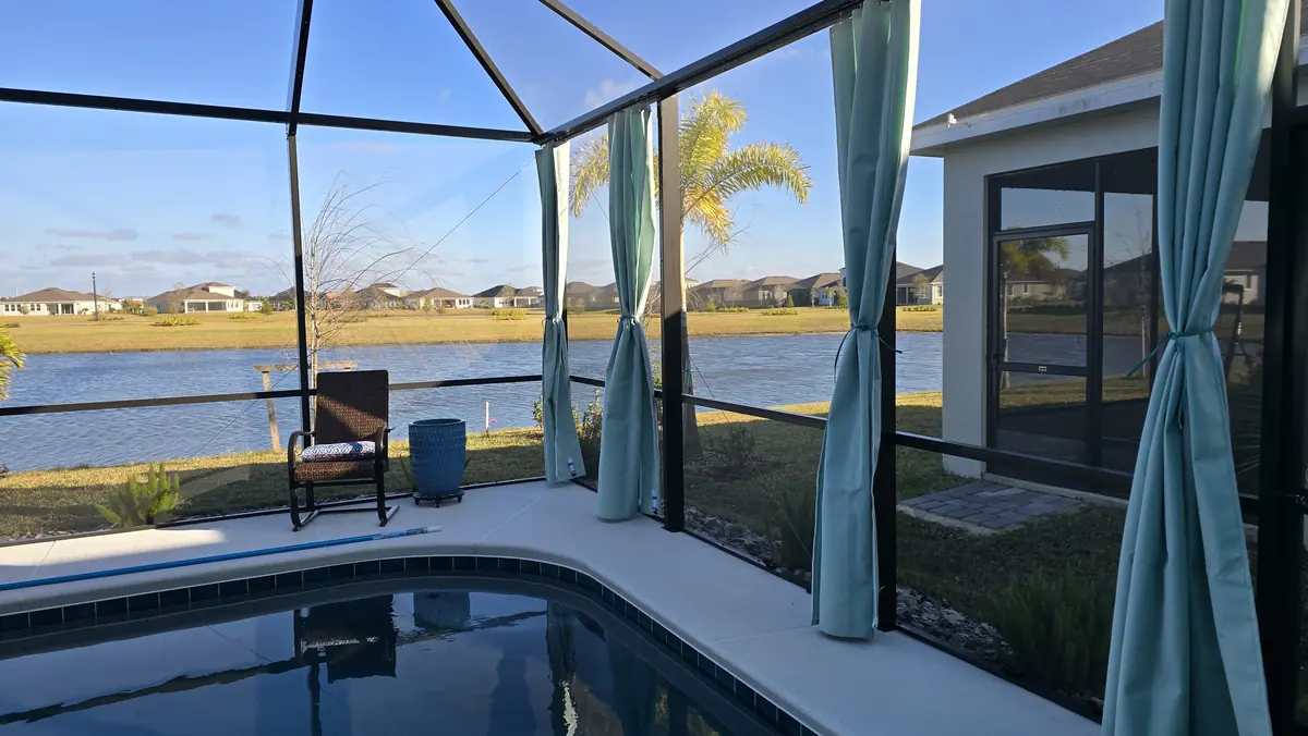 Aqua tie-back privacy curtains around a pool with a lake behind