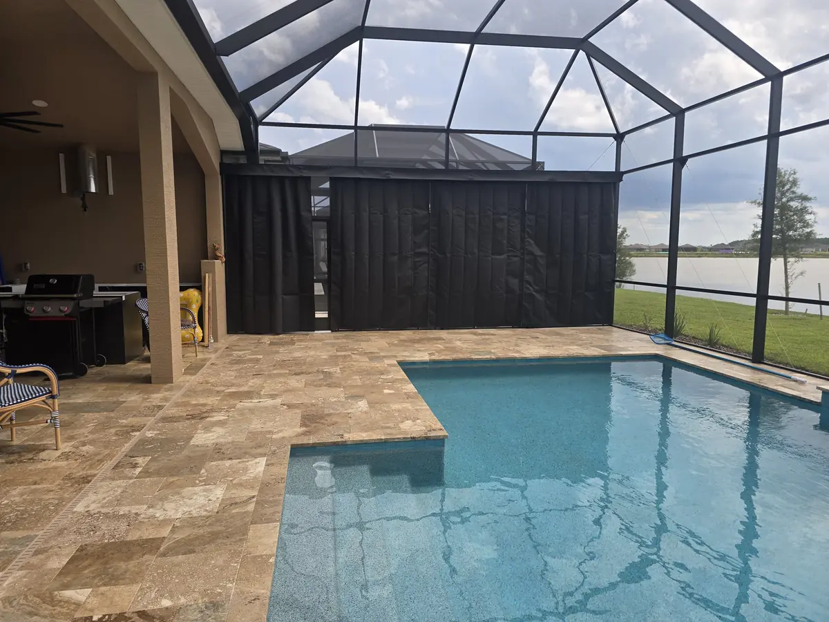 Black privacy curtains along a lakefront lanai and pool in a Florida screen enclosure