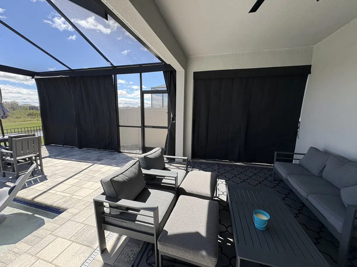 Black privacy curtains around a patio lounge and dining set in a screen enclosure