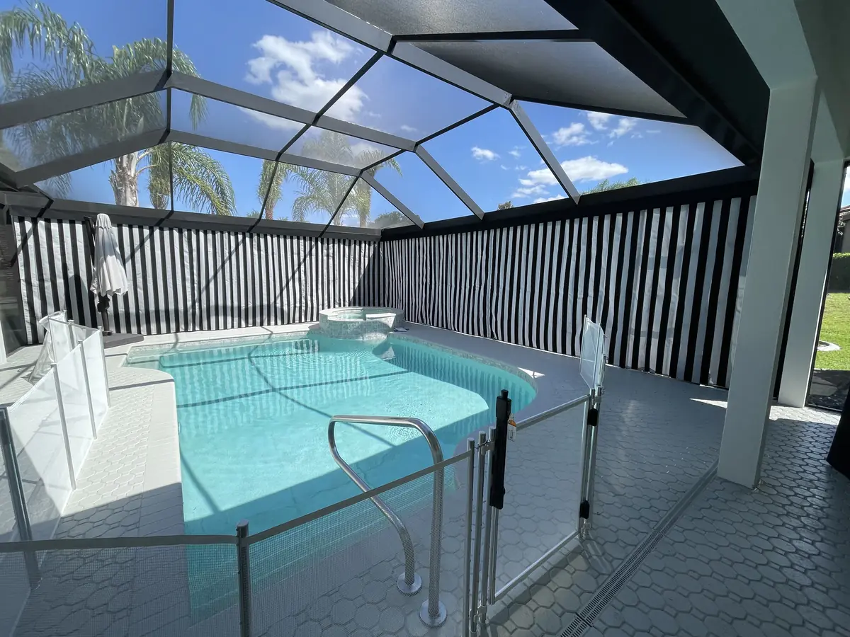 Black and white striped privacy curtains around a pool inside a Florida screen enclosure