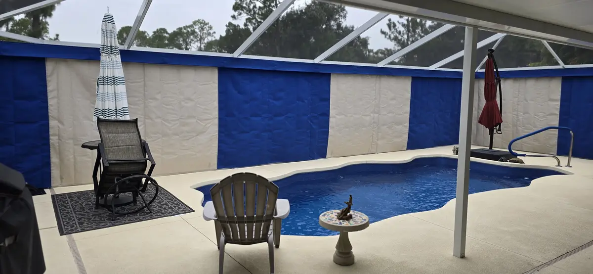Blue and cream Sunbrella outdoor curtains around Florida pool enclosure