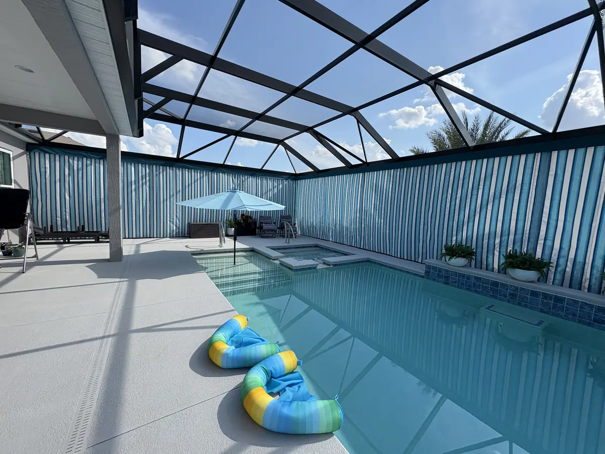 Wide view of blue and white striped privacy curtains around a pool cage