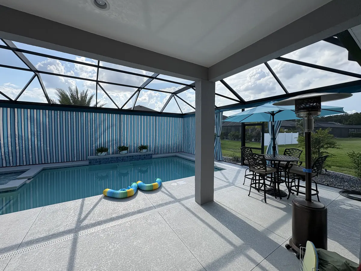 Blue and white striped privacy curtains around a pool in a Florida screen enclosure