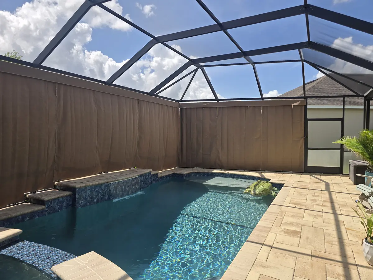 Brown privacy curtains around a pool and spa in a bronze Florida screen enclosure