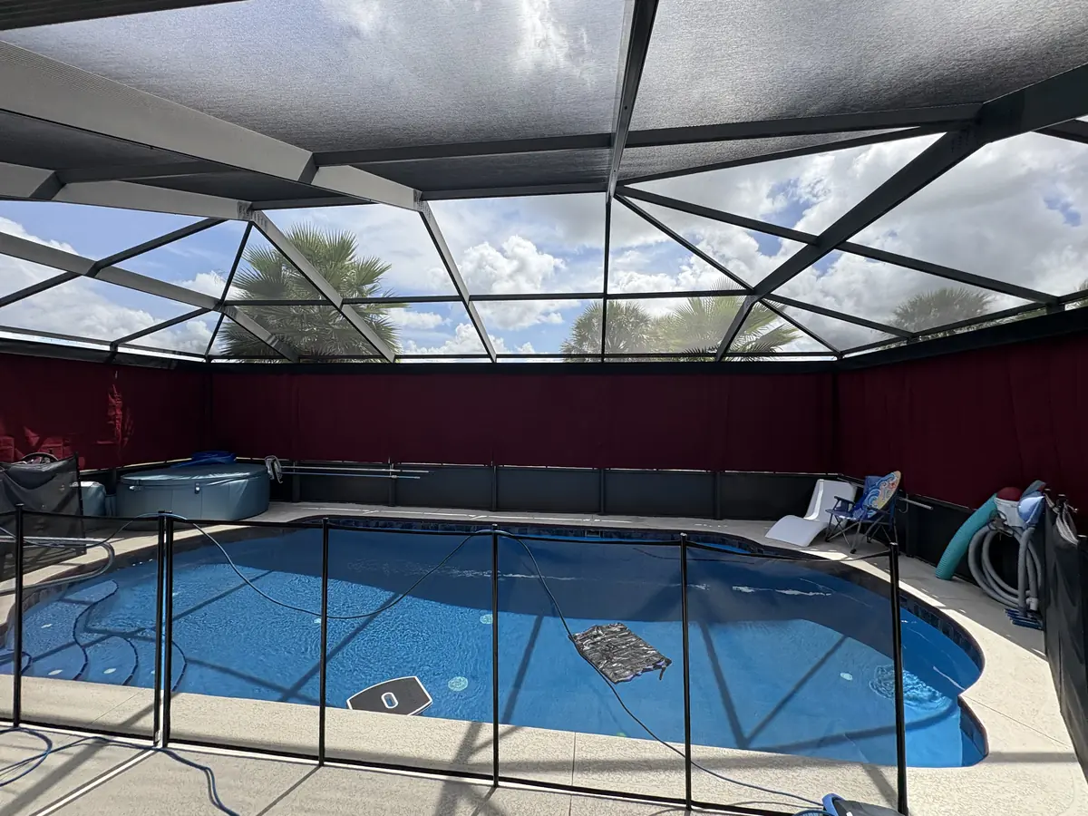Burgundy privacy curtains wrapping a pool cage with a child safety fence