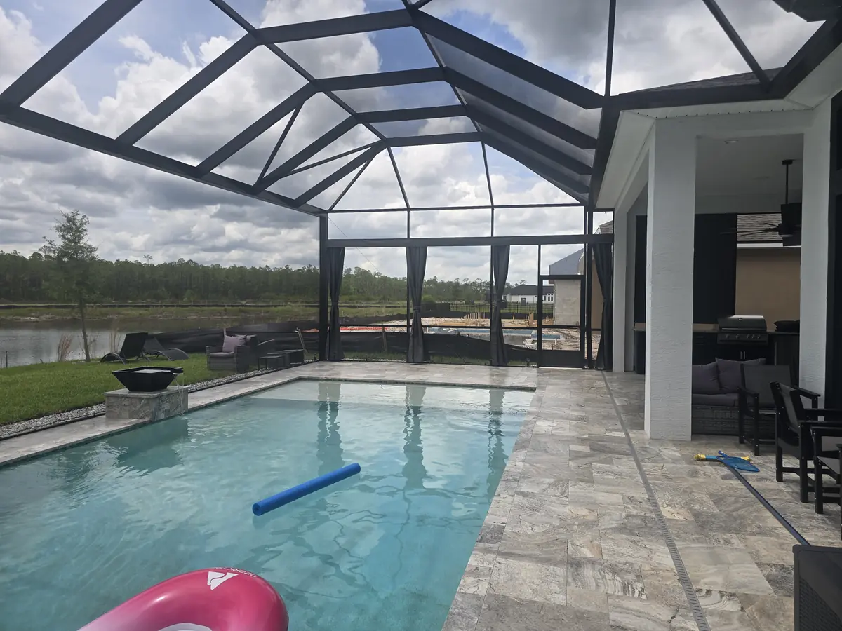 Charcoal privacy curtains along a lakefront pool enclosure with covered lanai