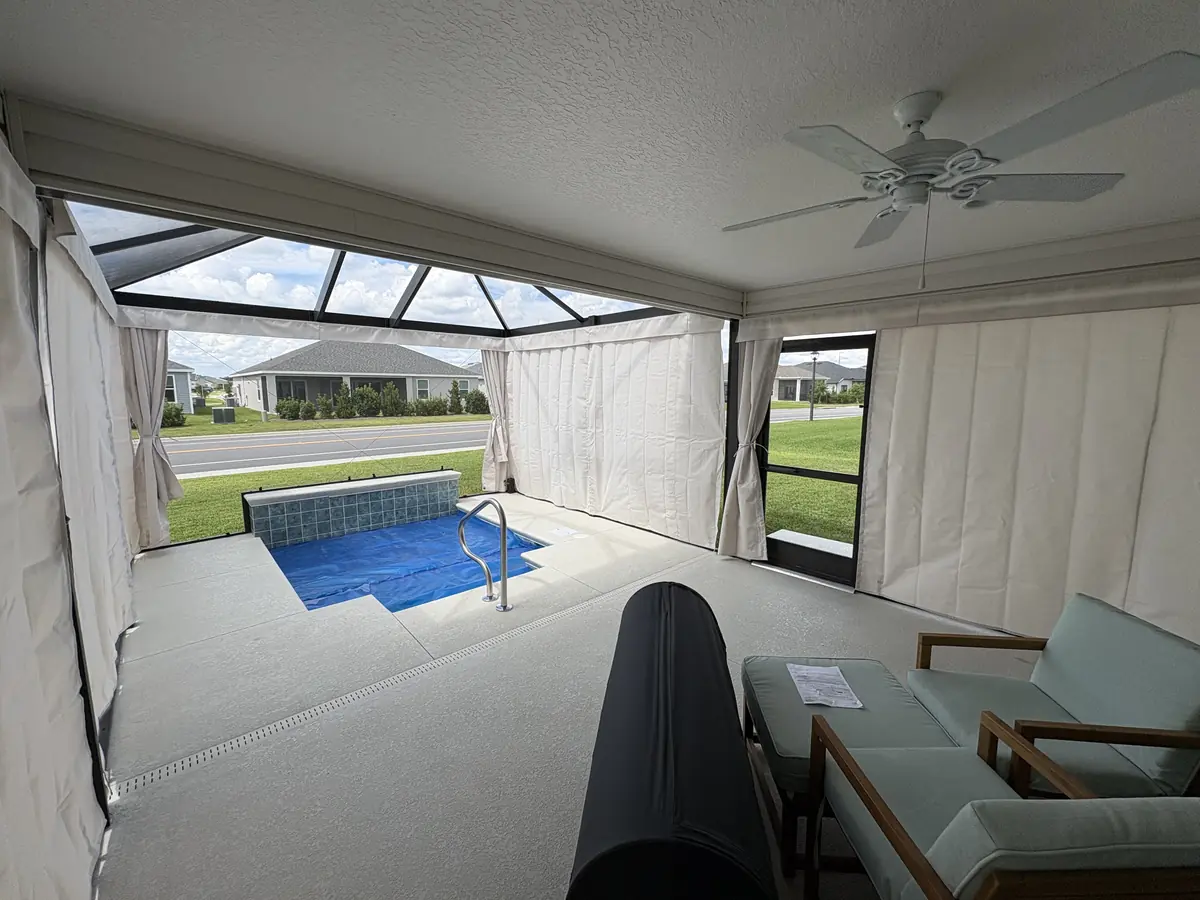 Cream privacy curtains around a lanai with a small spa