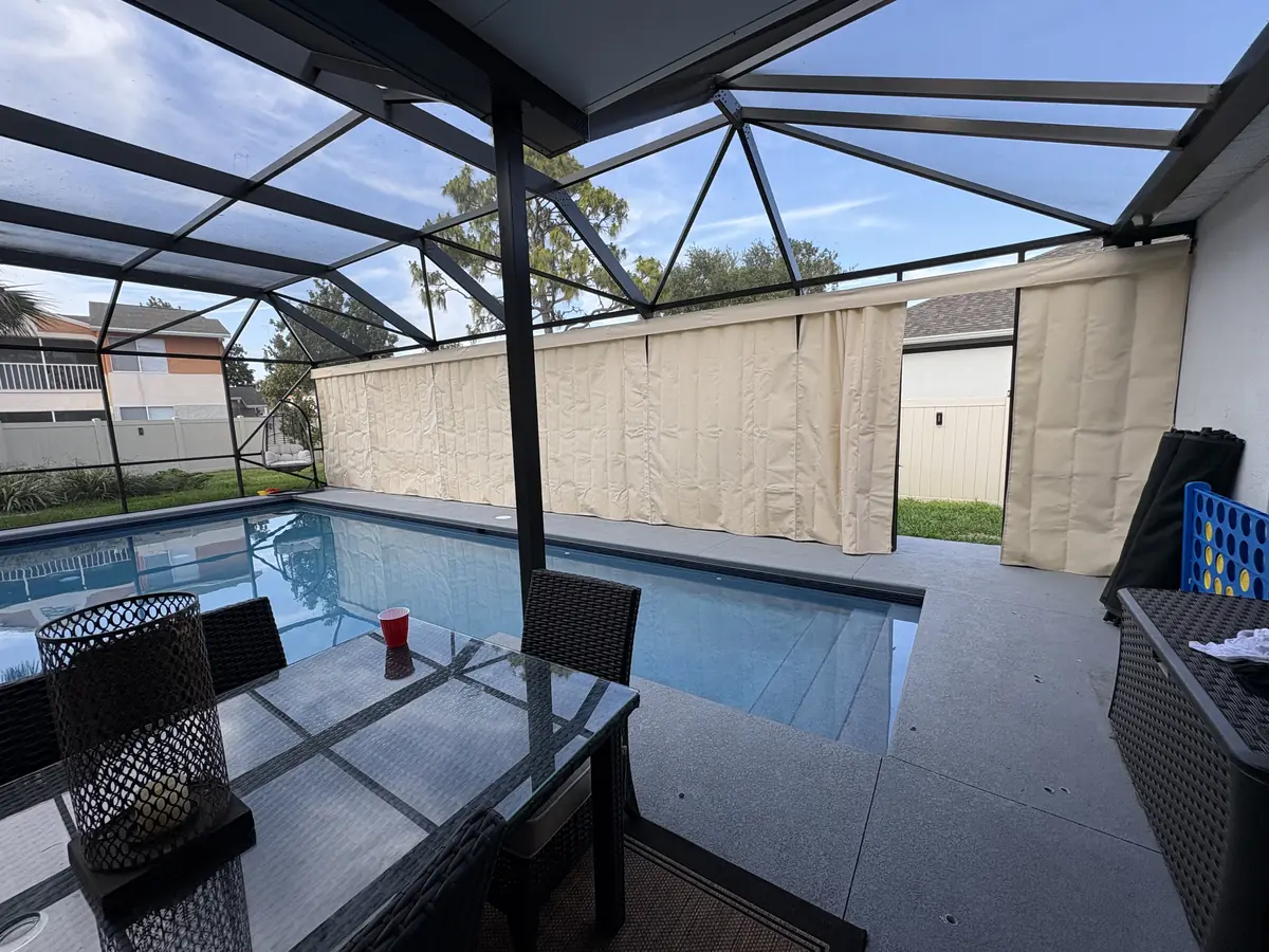 Cream privacy curtains around a pool and spa on a lanai in Florida