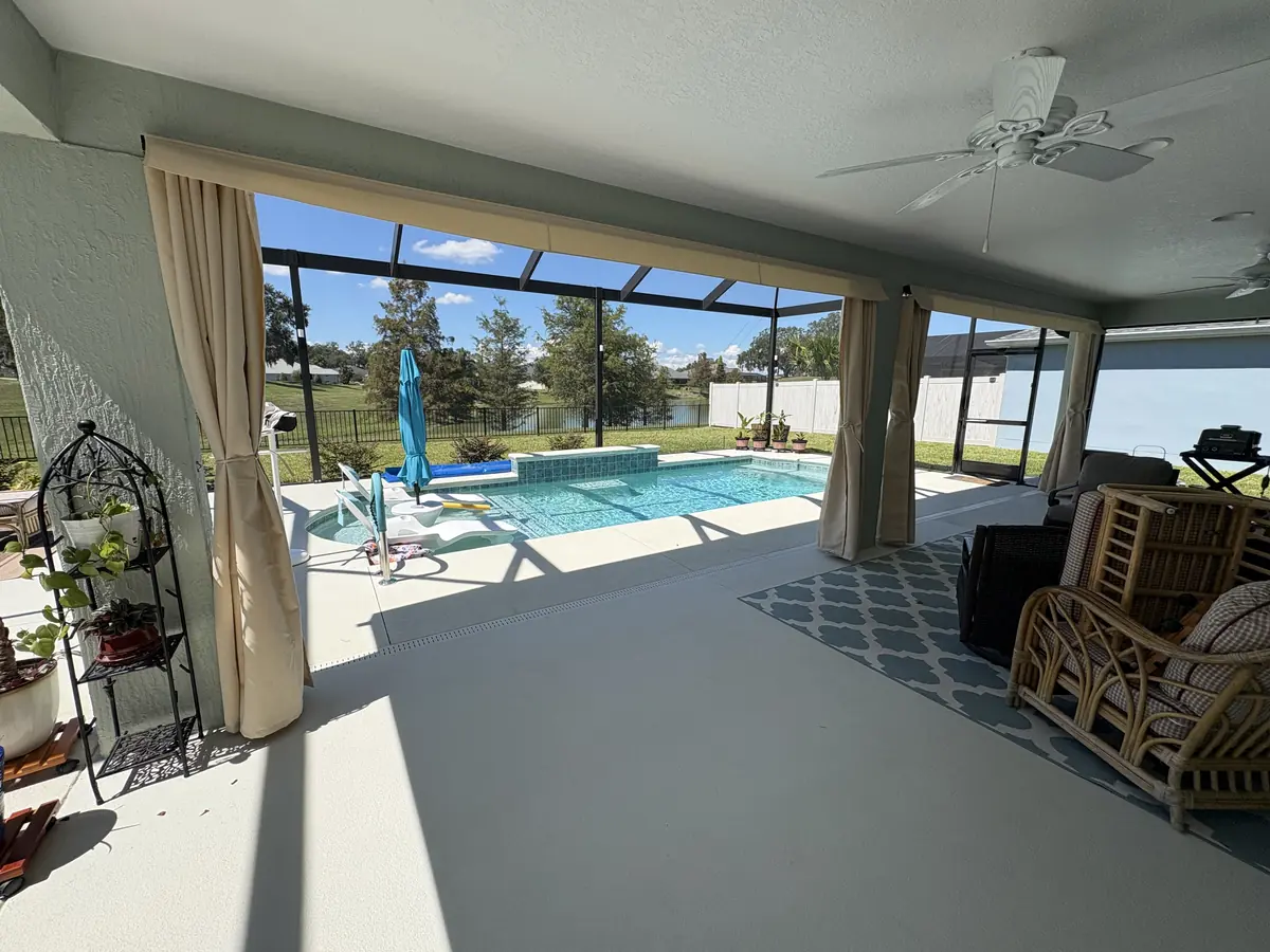 Cream tie-back privacy curtains on a covered lanai overlooking a pool