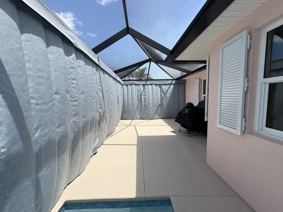Gray privacy curtains wrapping both sides of a pool in a Florida screen enclosure