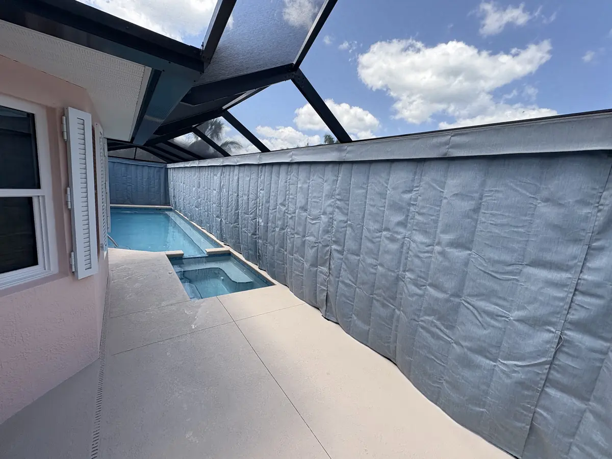 Gray privacy curtains around a spa corner of a Florida pool enclosure