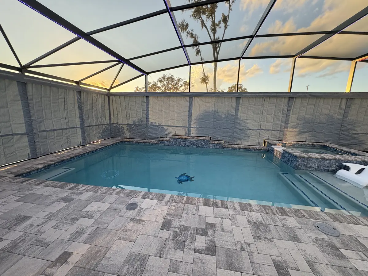 Gray privacy curtains around a pool at sunset in a Florida screen enclosure