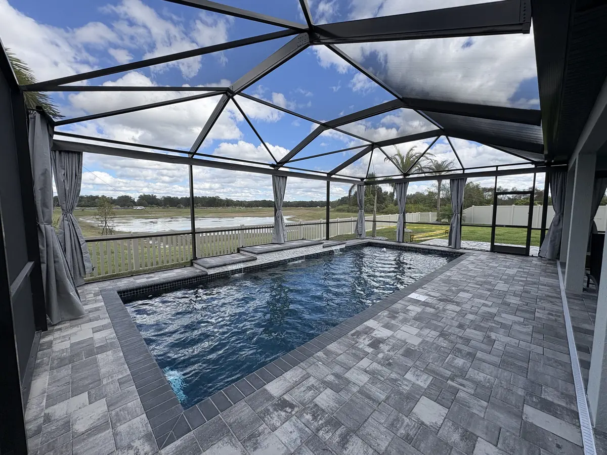 Gray tie-back privacy curtains around a lakefront pool and lanai