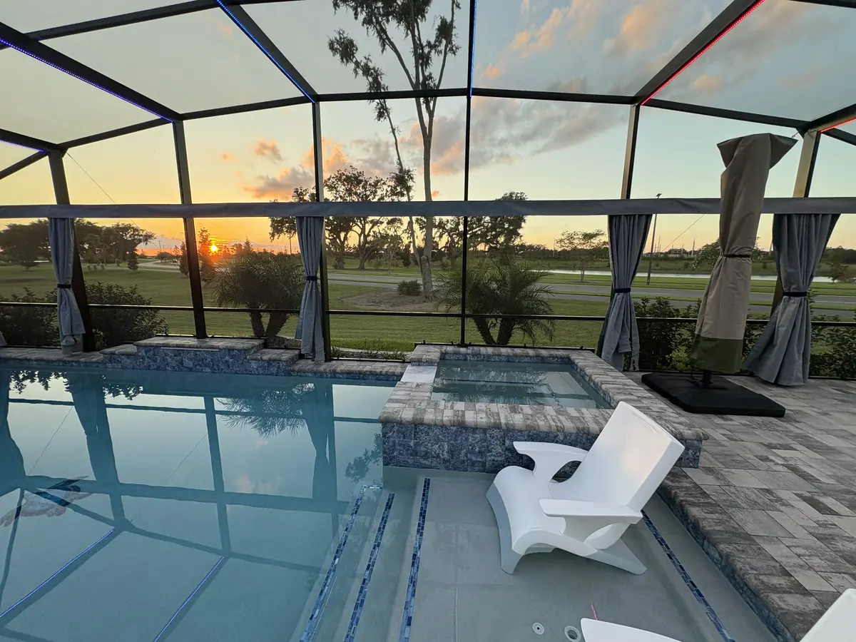 Gray tie-back privacy curtains around a pool and spa at sunset