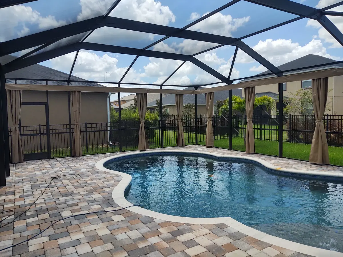 Pool cage privacy curtains around kidney-shaped pool