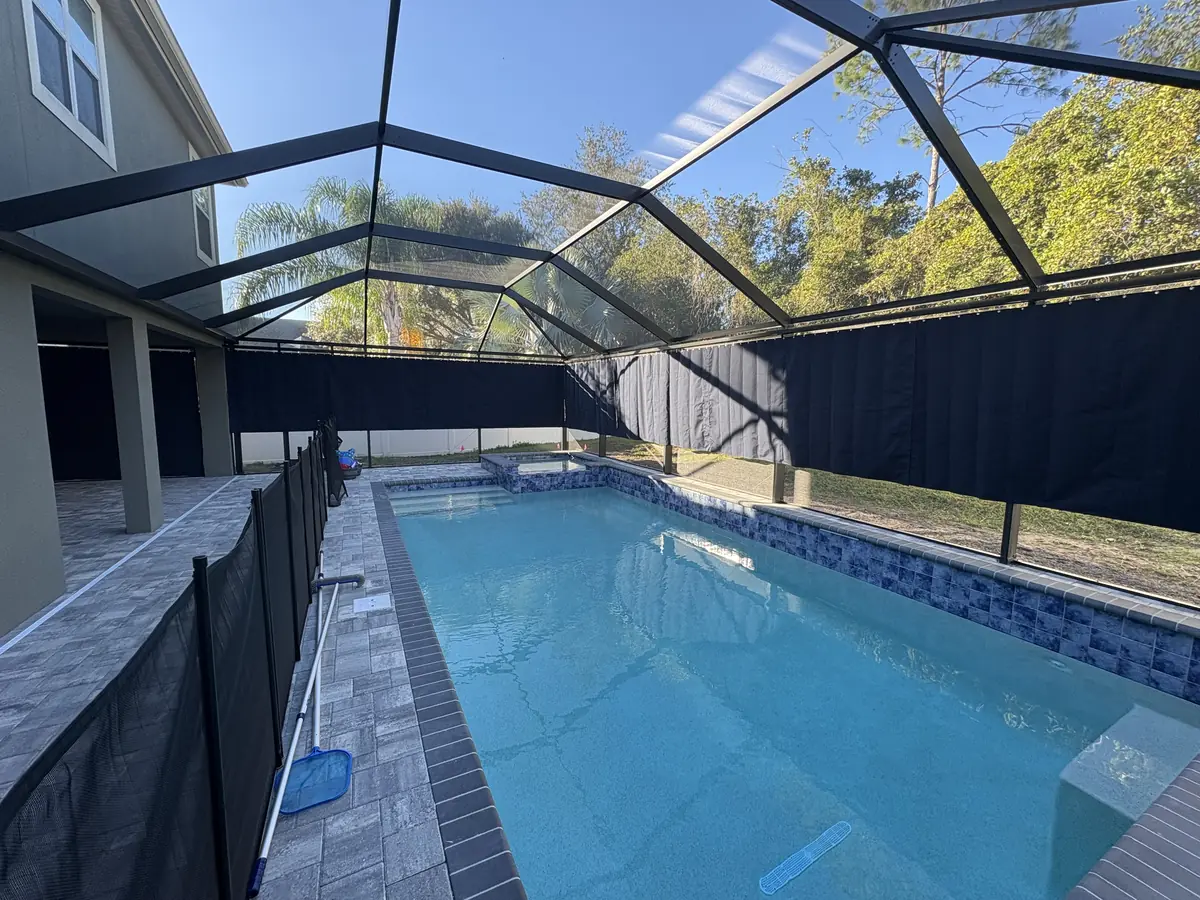 Navy privacy curtains around a pool with a child safety fence in a Florida pool enclosure