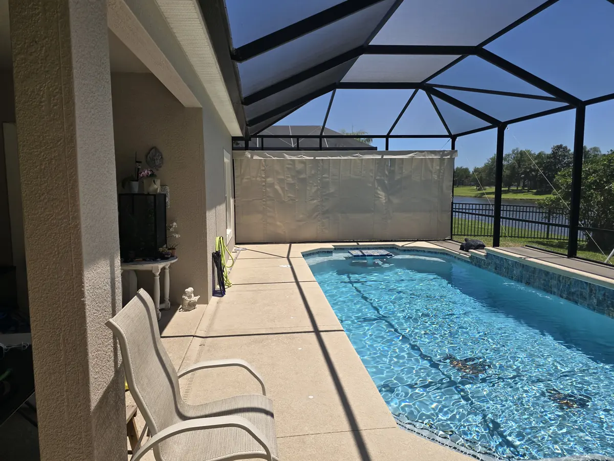 Sand colored privacy curtain panel beside a pool with a lake view in Florida