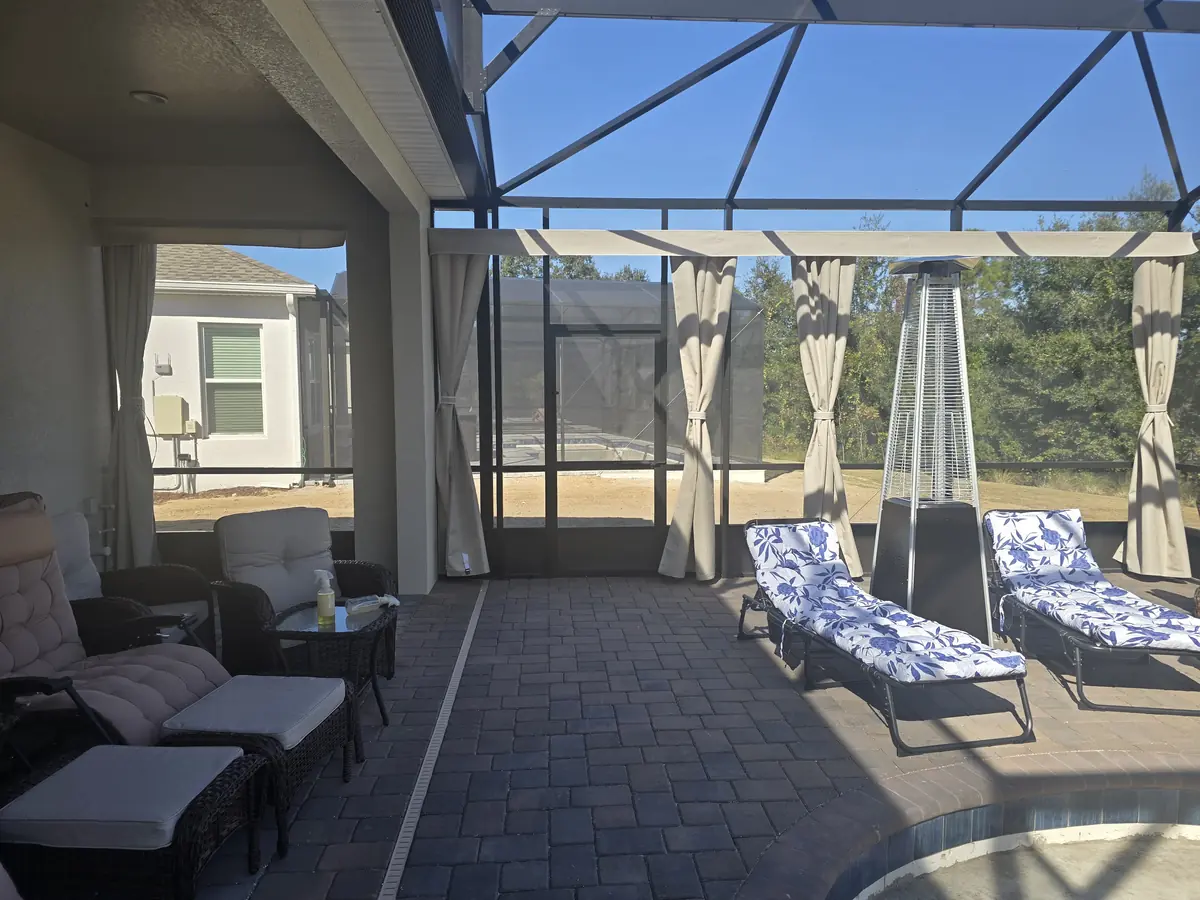 Light sheer-style white curtains tied back on a lanai with lounge chairs and a fire pit heater