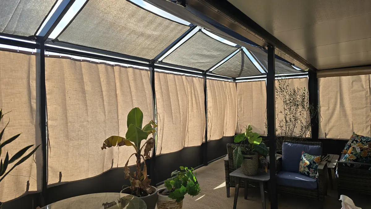 Tan privacy curtains around a covered lanai with potted plants and seating