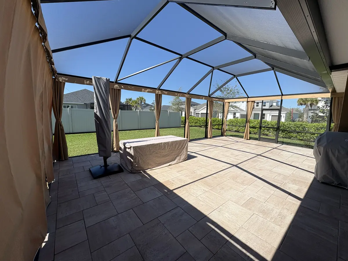 Tan tie-back privacy curtains around a paver patio inside a bronze screen enclosure