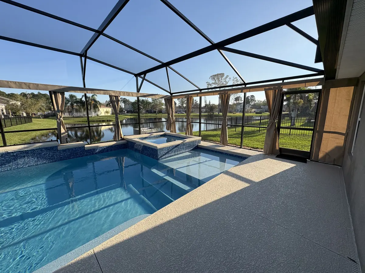 Tan tie-back privacy curtains around a lakefront pool and spa in a Florida screen enclosure
