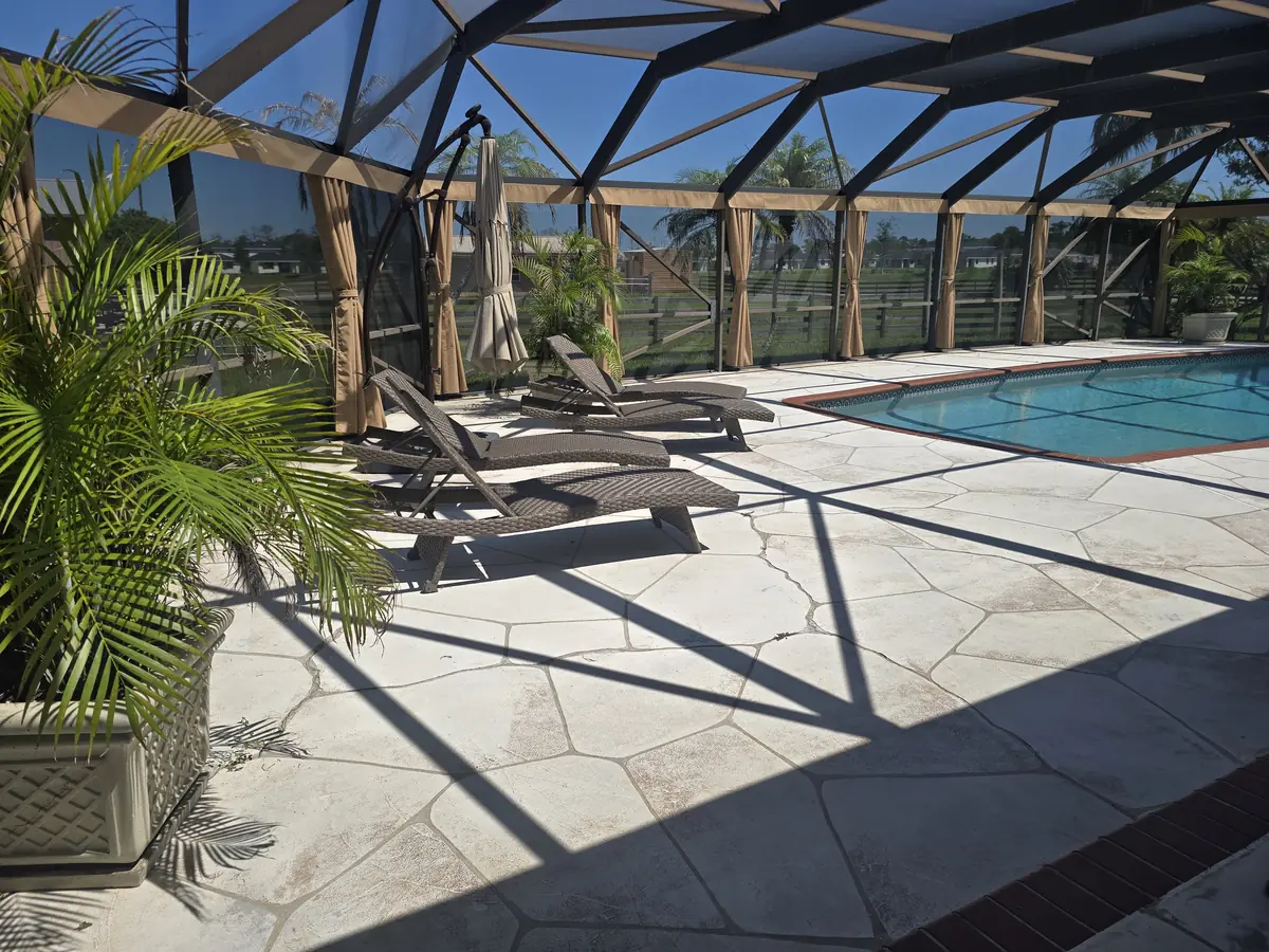 Tan tie-back privacy curtains around a pool deck with lounge chairs and potted palms