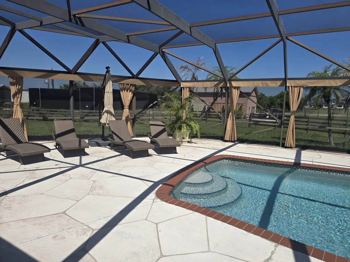 Tan tie-back privacy curtains around a large pool deck with loungers in Florida
