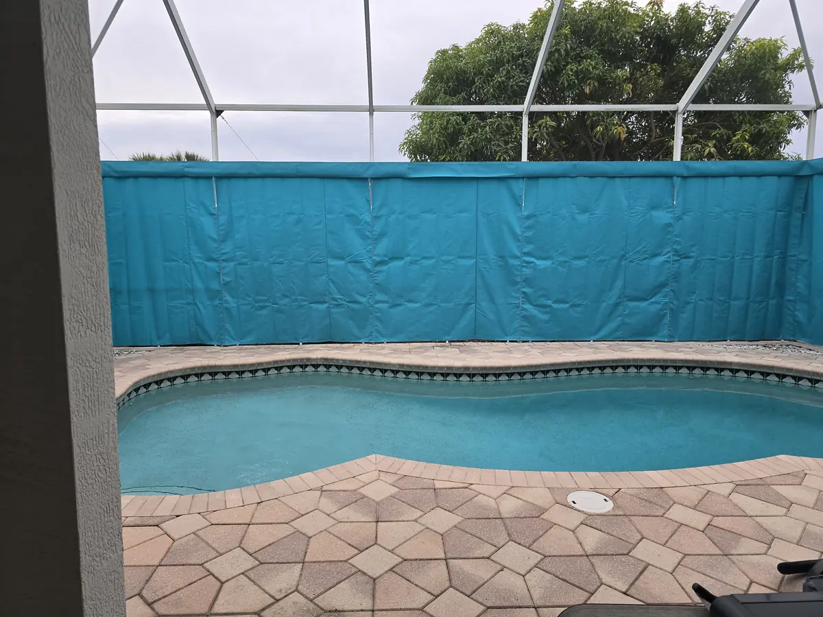 Teal privacy curtains wrapping two sides of a Florida pool cage