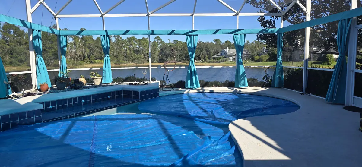 Teal tie-back privacy curtains around a pool overlooking a lake in Florida