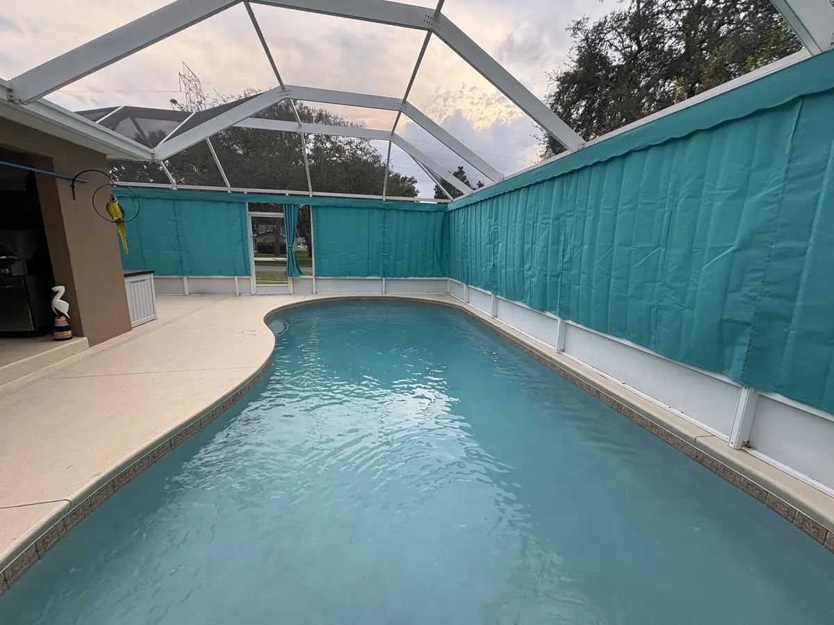 Turquoise privacy curtains wrapping a pool and spa in a white screen enclosure