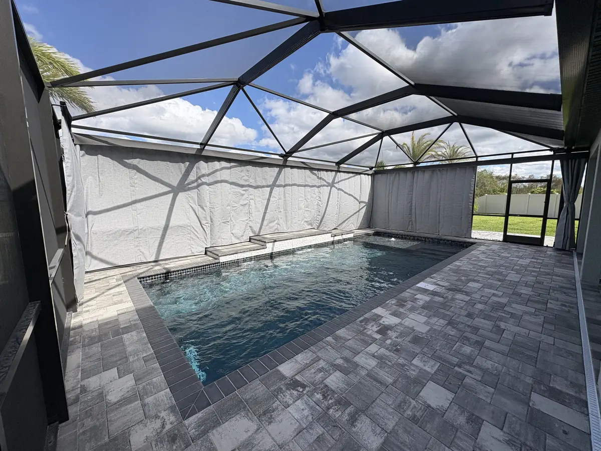 White privacy curtains along a lap pool in a Florida screen enclosure