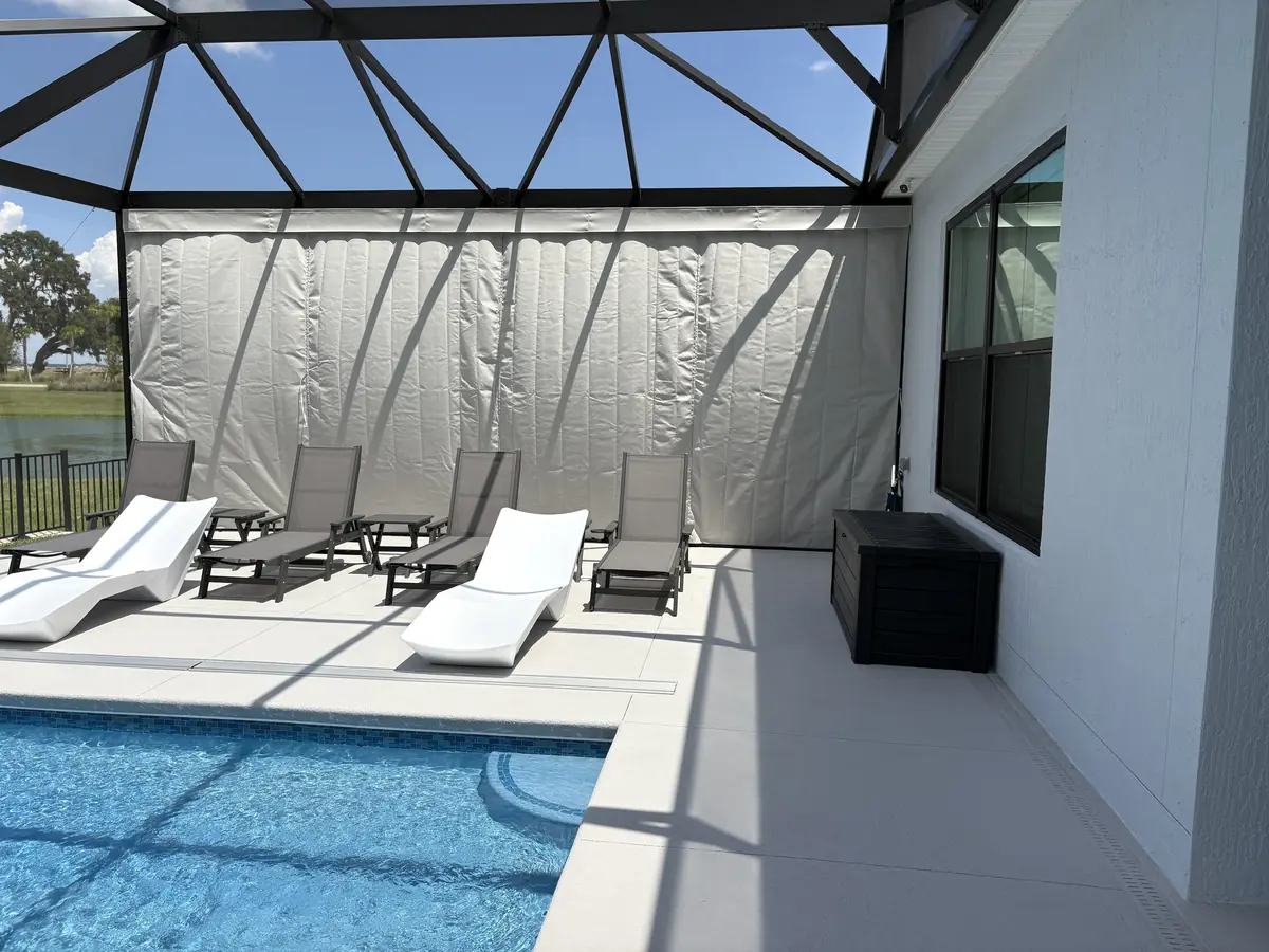 White privacy curtains around a modern pool deck with loungers in a Florida lanai