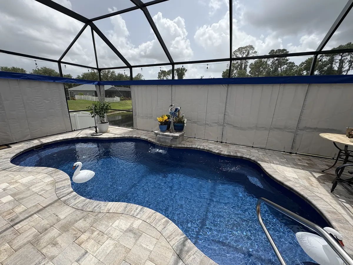 White privacy curtains with a navy valance around a pool in a Florida screen enclosure