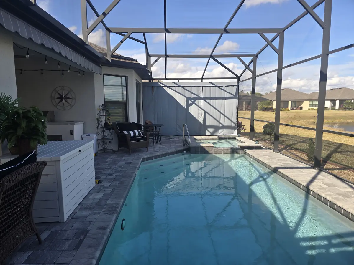White privacy curtains around a pool and spa in a white aluminum screen enclosure
