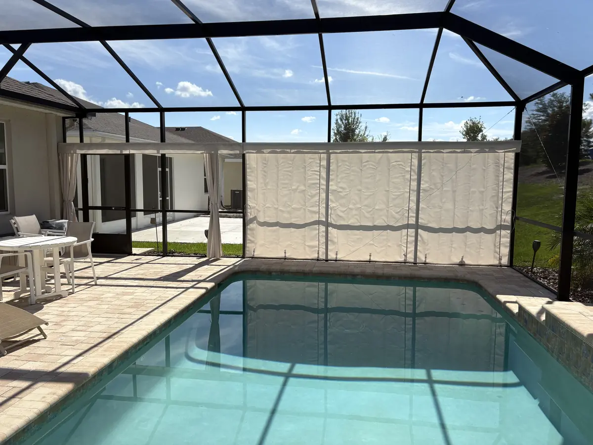 White privacy curtains along the back wall of a pool cage in Florida