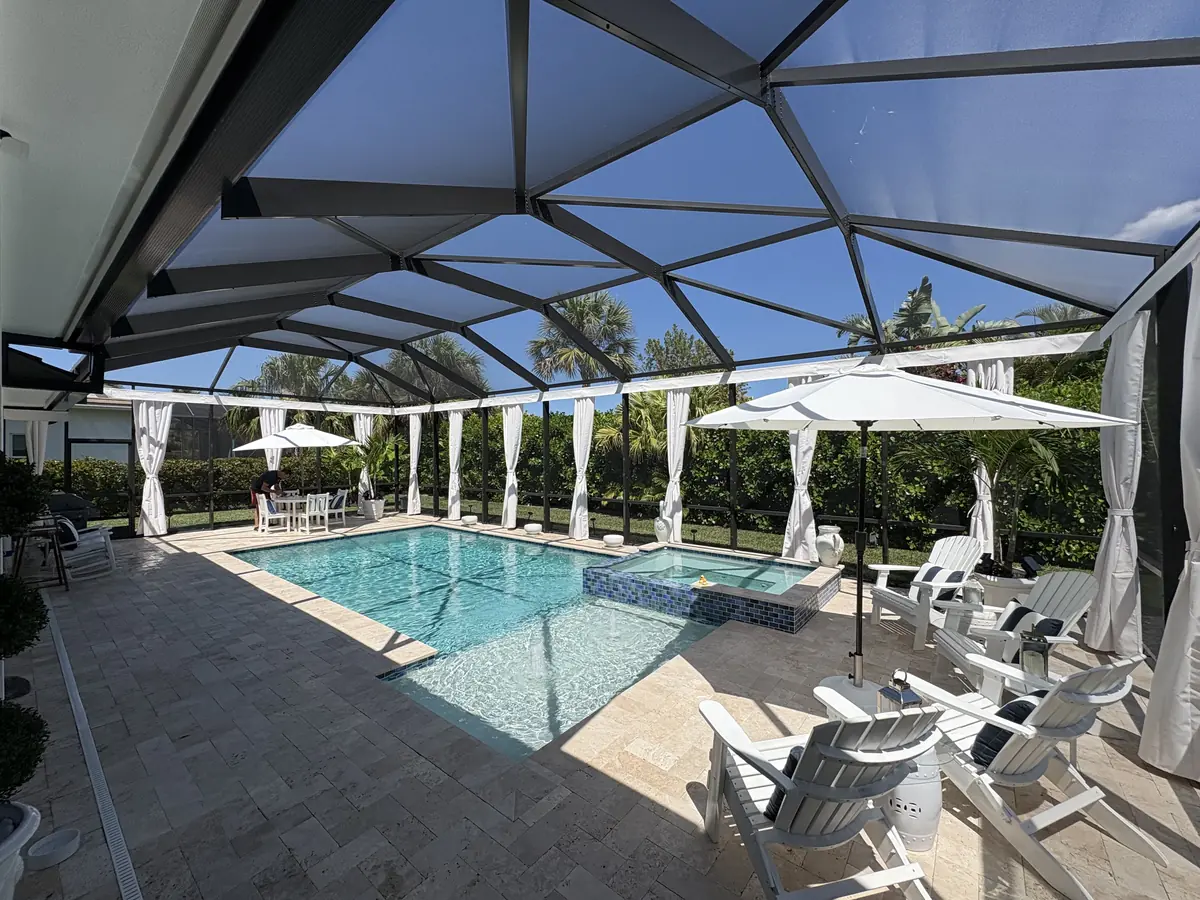 White tie-back privacy curtains around a pool deck with white patio umbrellas