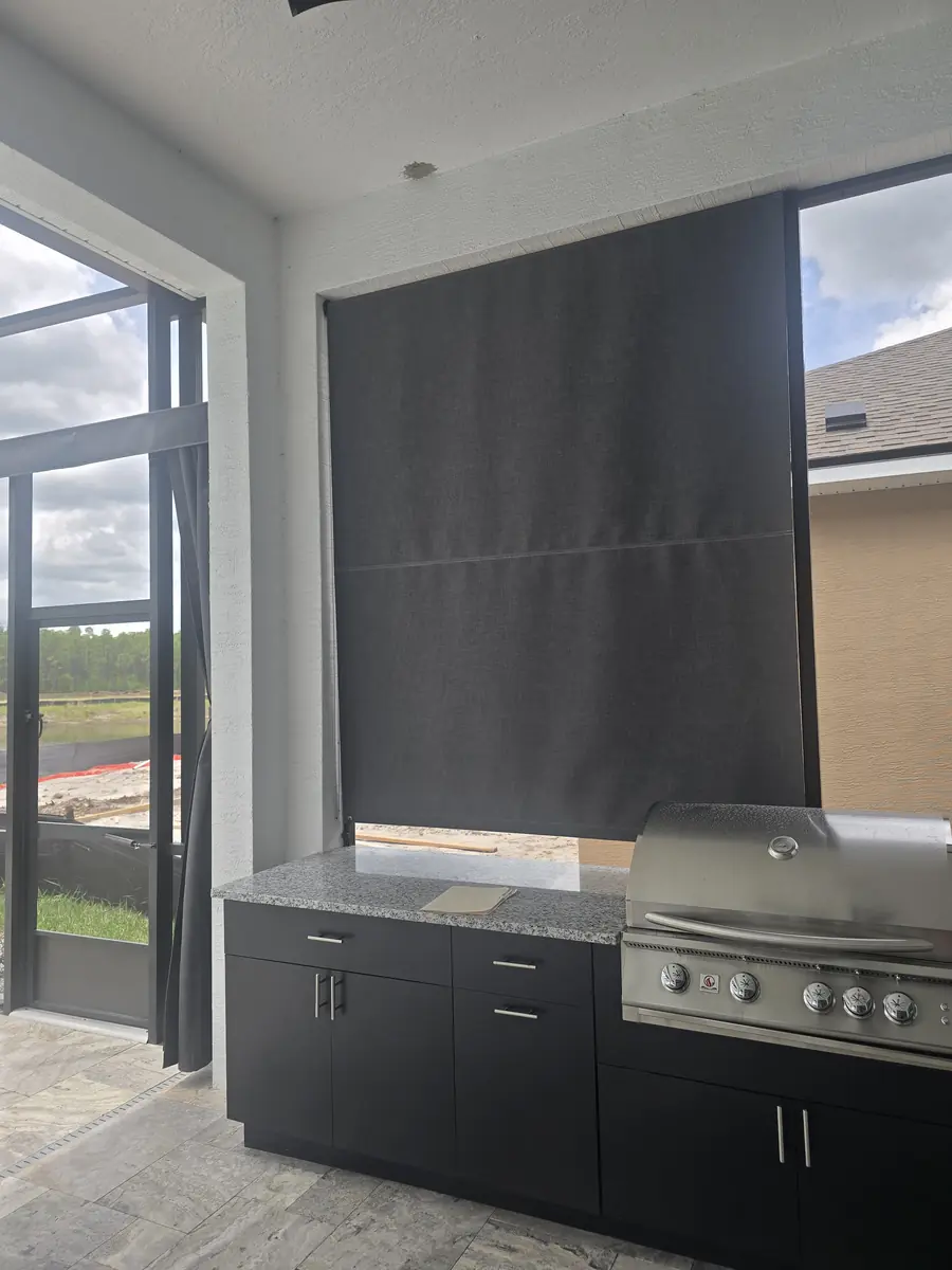 Charcoal roller shade behind an outdoor kitchen grill on a Florida lanai