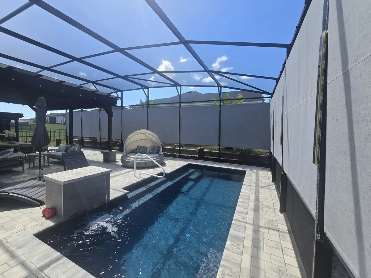 Gray roller shades lowered along a pool and spa enclosure in Florida