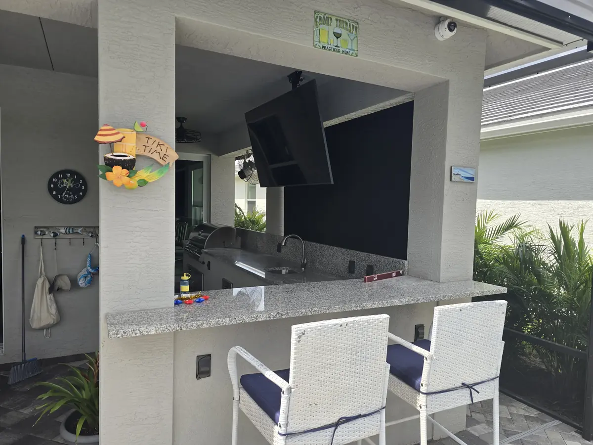 Roller shade protecting an outdoor kitchen and TV on a Florida lanai