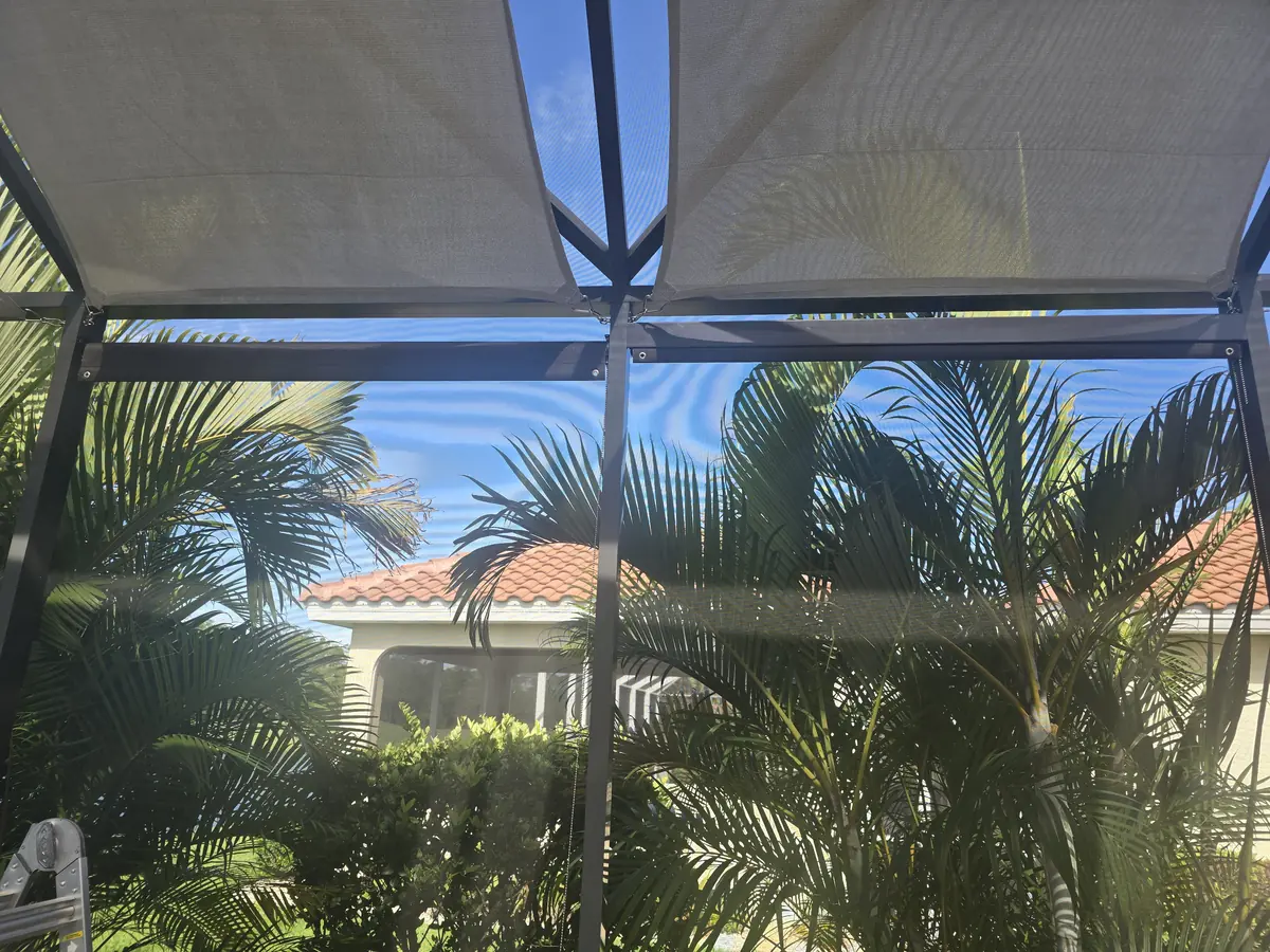 Sand colored roller shade lowered on a lanai with palm trees outside