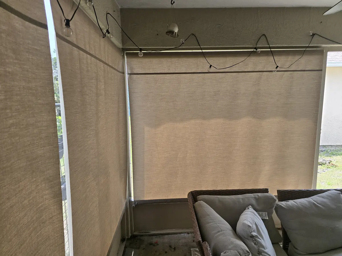 Tan roller shades lowered around a lanai sectional sofa