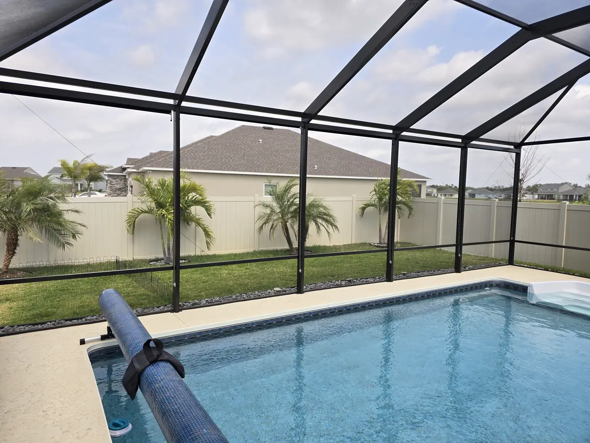 Tan roller shade lowered on a pool cage wall beside a pool in Florida