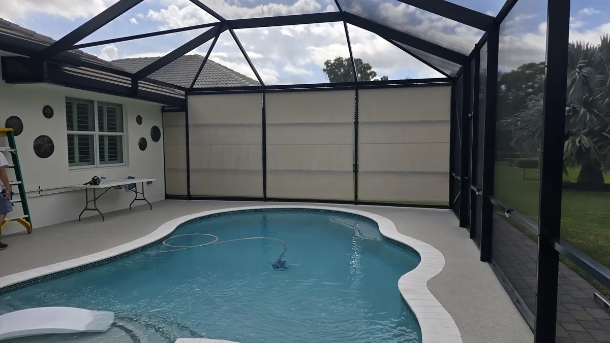 White roller shades covering the full back wall of a Florida pool enclosure