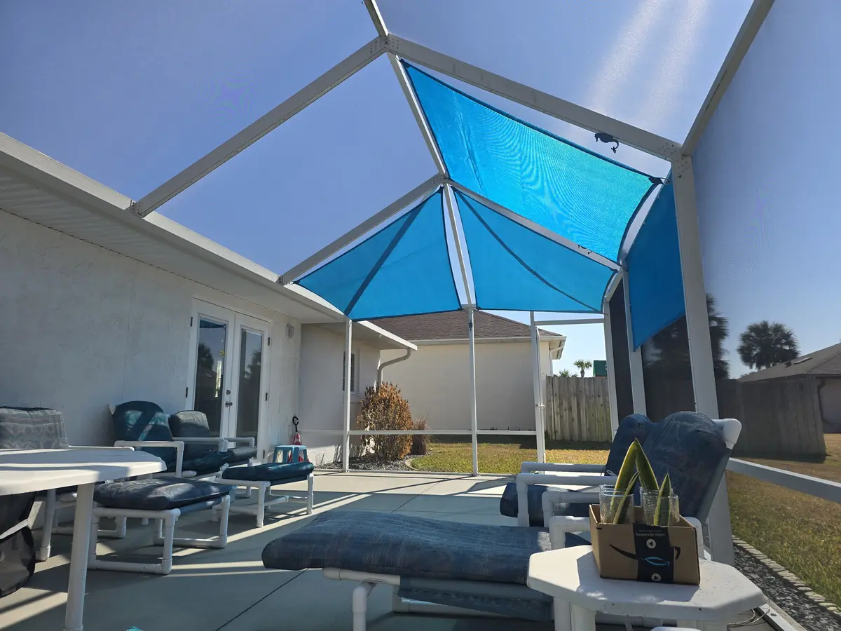 Aqua blue shade sail over a lanai seating area in a white screen enclosure