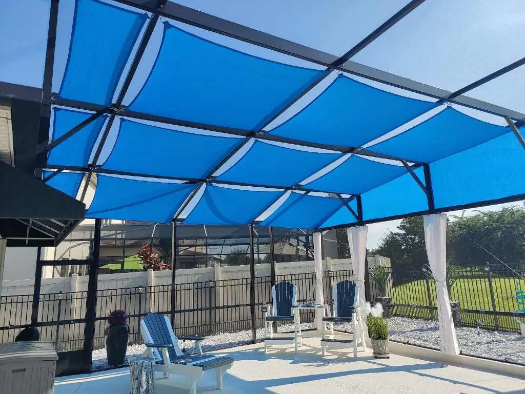 Blue shade sails over a lanai with lounge chairs and a view of the lawn