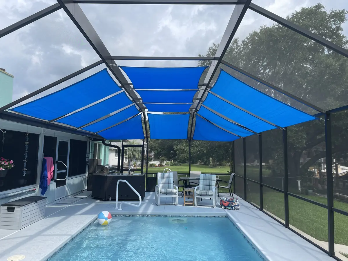 Blue shade sails over a pool cage with lounge chairs along the pool deck