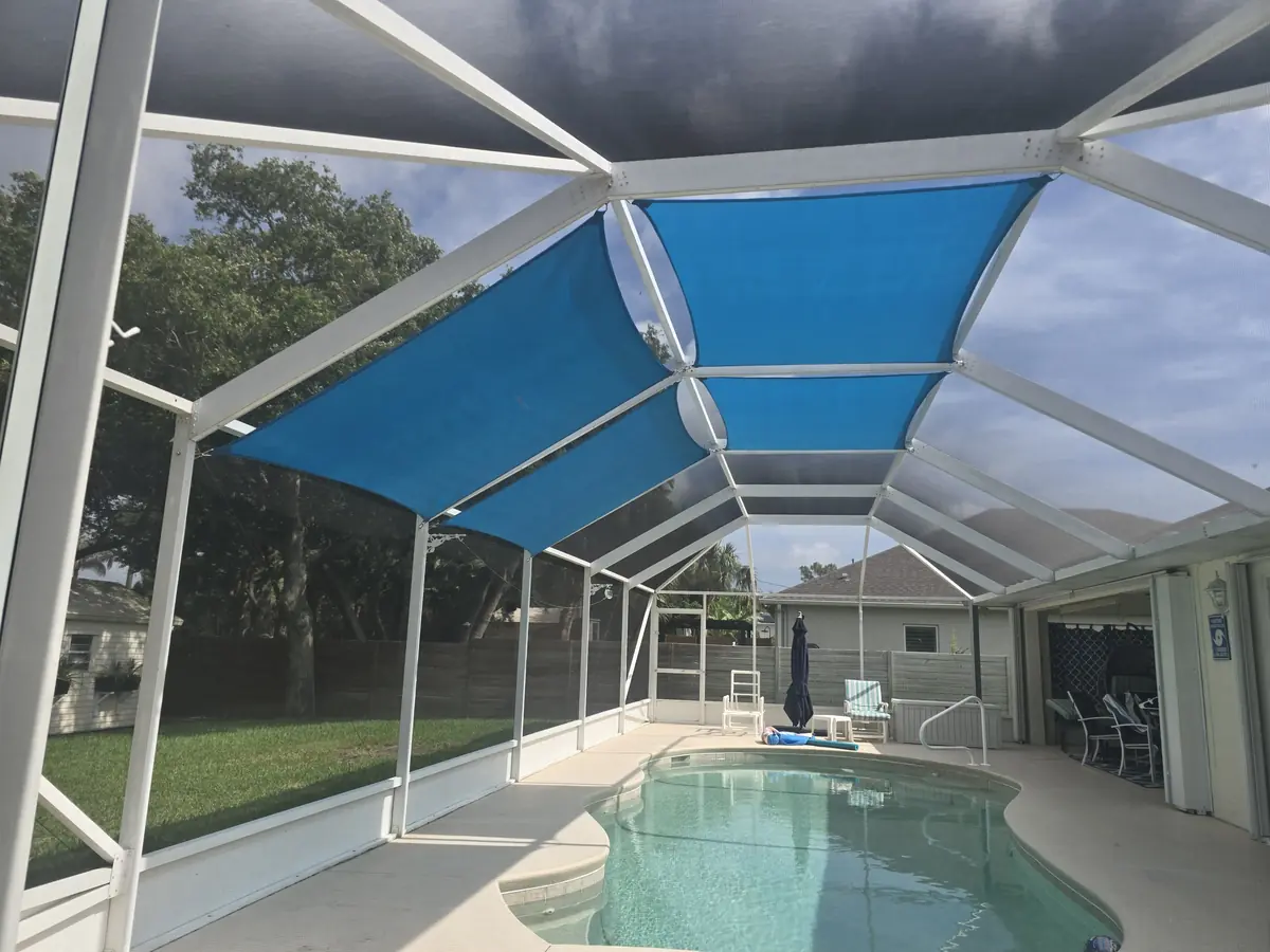 Wide view of blue shade sails over a pool inside a white Florida screen enclosure
