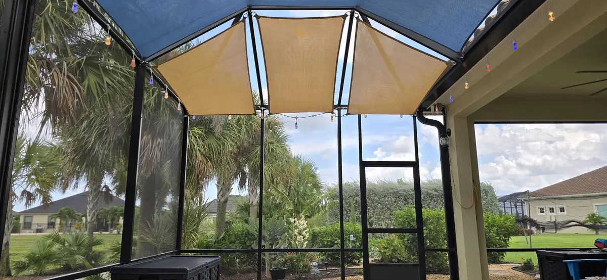Blue and tan shade sails with string lights over a lanai in a Florida pool cage