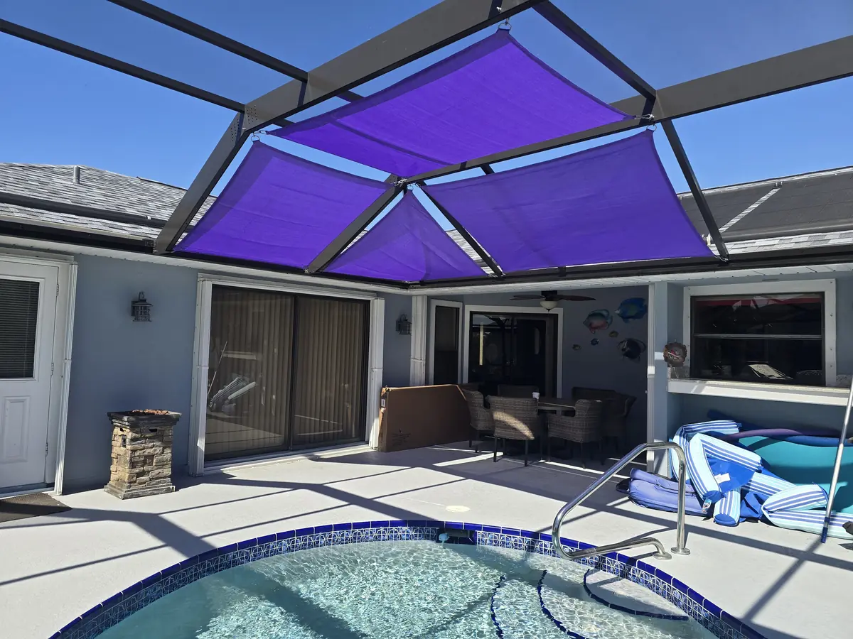 Purple shade sails over a covered lanai seating area next to a pool
